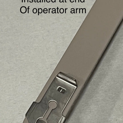 Metal clip labeled 'Example Of clip 221 Installed at end Of operator arm' on a gray background